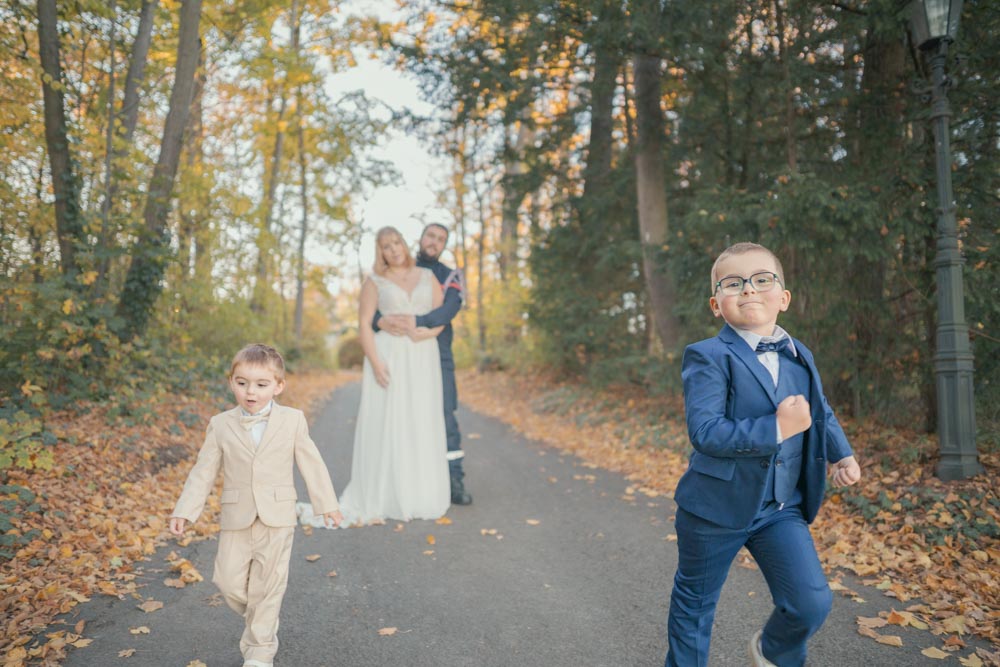Deux enfants s'éloignant de leurs parents côté photographe dans une allée arborée en automne