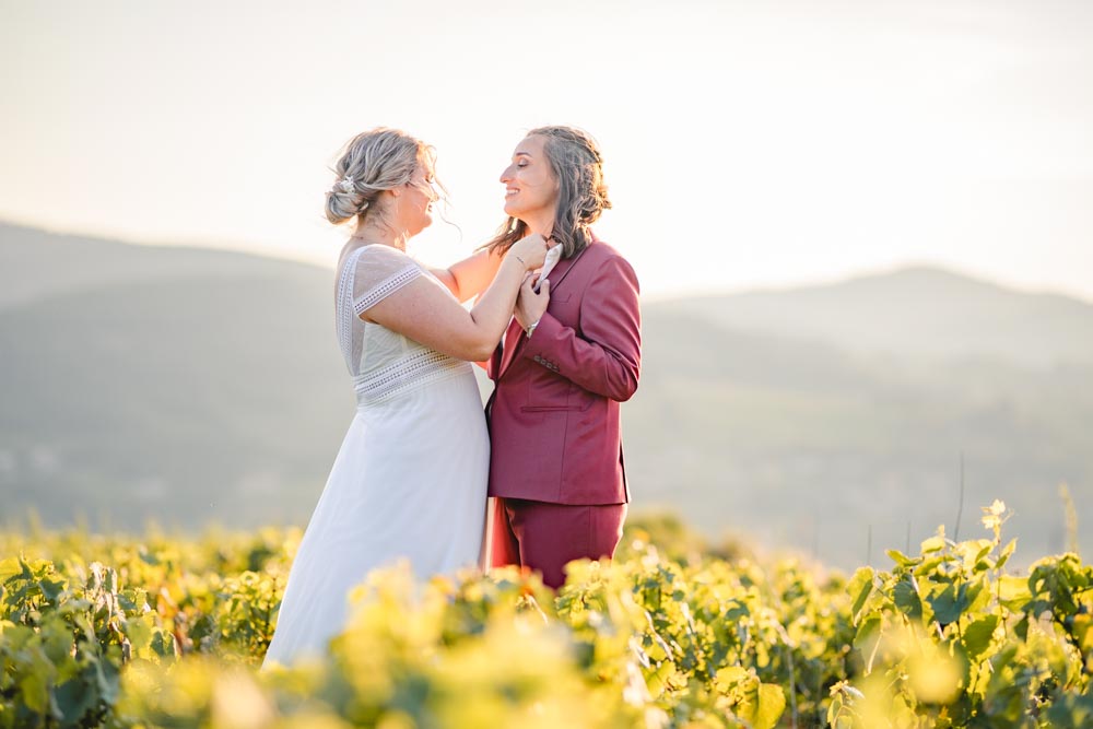 Plan large d'un couple ajustant leur tenue au milieu des vignes au coucher de soleil