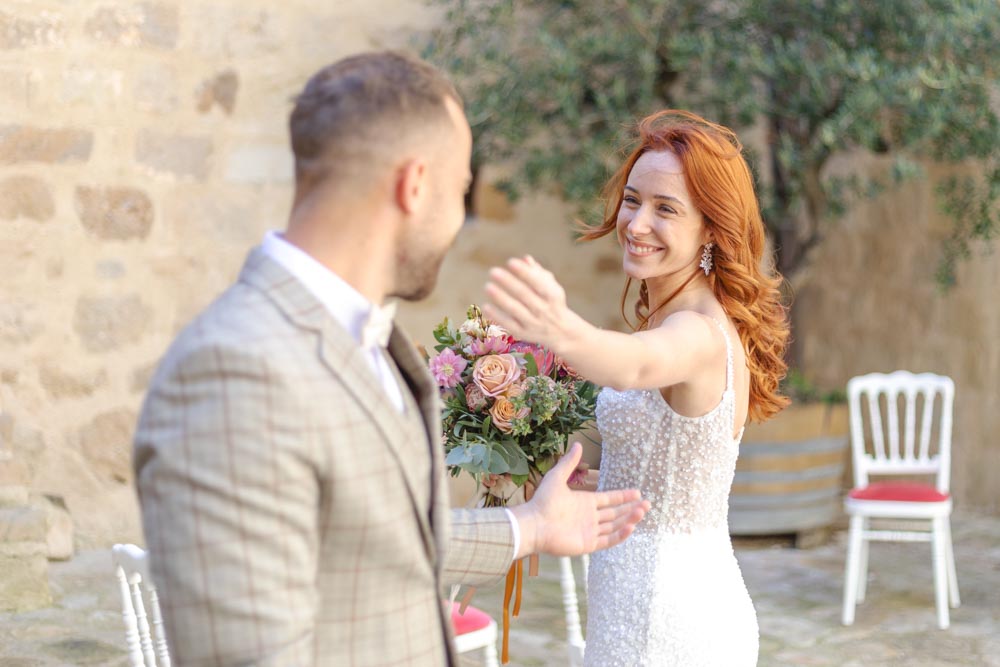 Portrait d'un couple de jeunes mariés l'un en face de l'autre et la mariée tendant le bras vers son époux