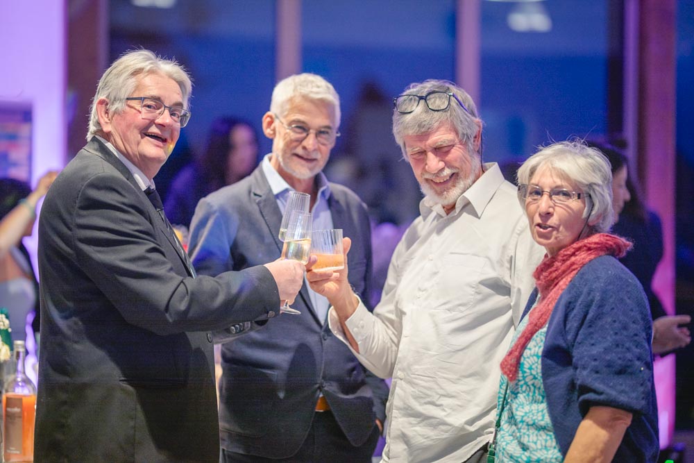 Invités trinquant lors d'une réception en intérieur avec une lumière d'ambiance violette