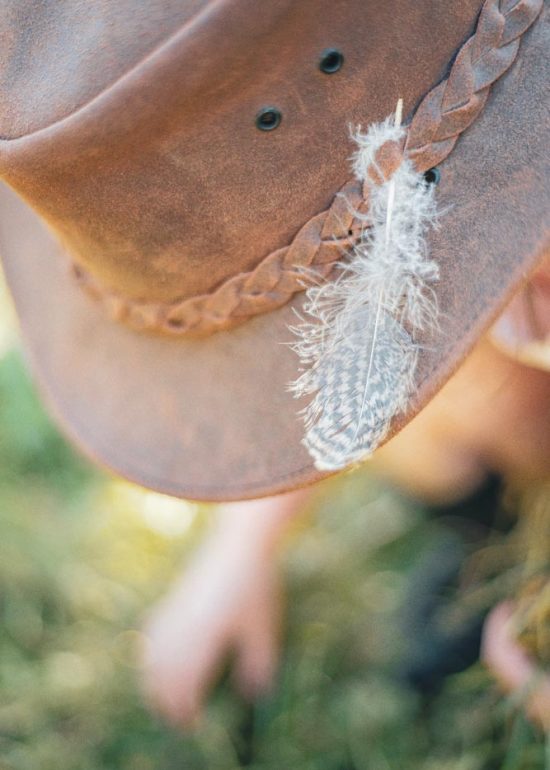 Détail d'un plume sur le chapeau d'une enfant jouant dans son jardin