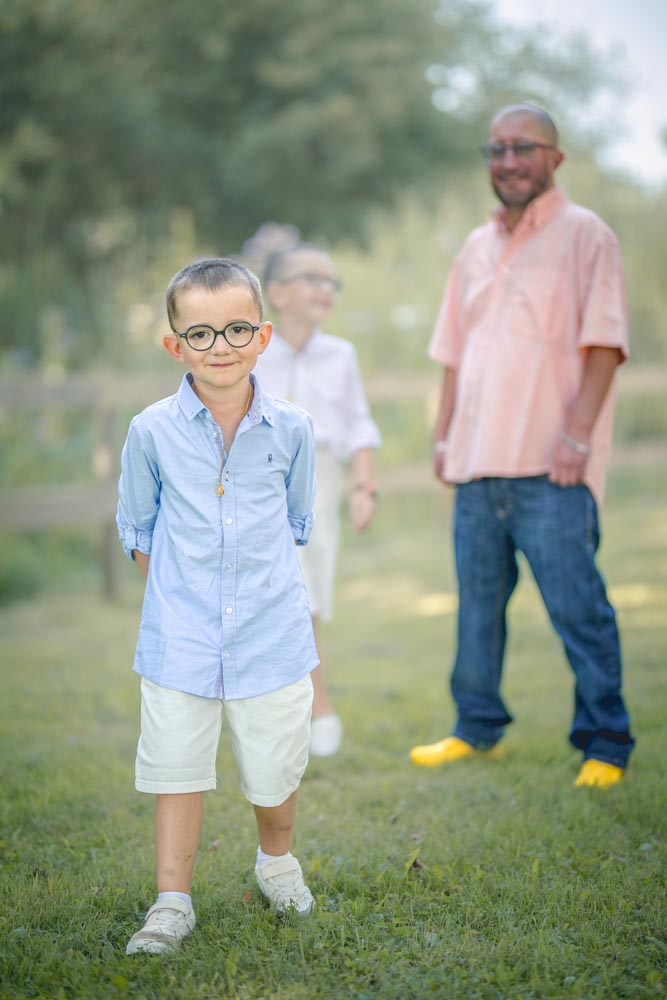 Enfant debout au devant de son frère et son père dans un parc verdoyant