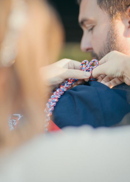 Photographie d'une femme remettant en place la fourragère de pompier sur l'épaule du costume de son mari