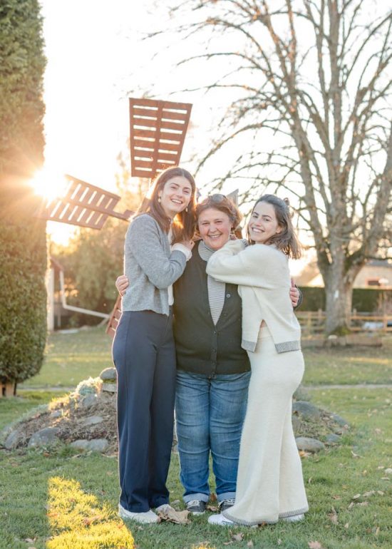 Plan large d'une mère et ses deux filles dans le jardin familial au coucher de soleil