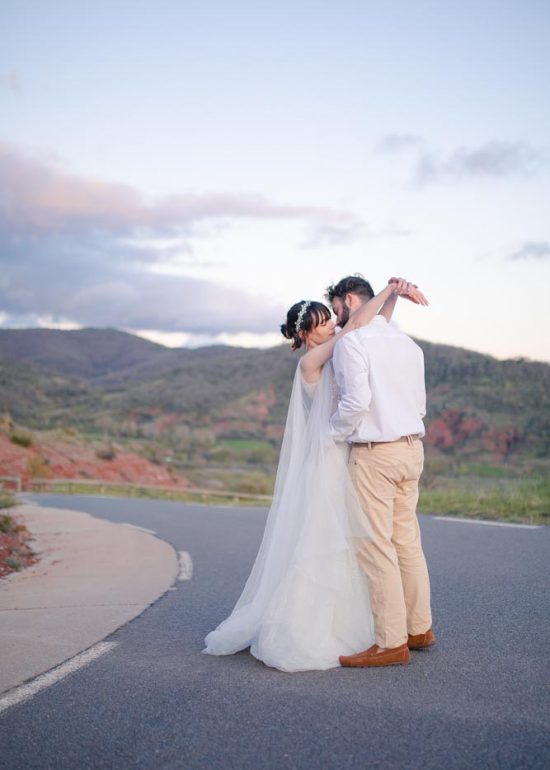 Plan large d'un couple enlacé sur une route de montagne à l'heure bleue