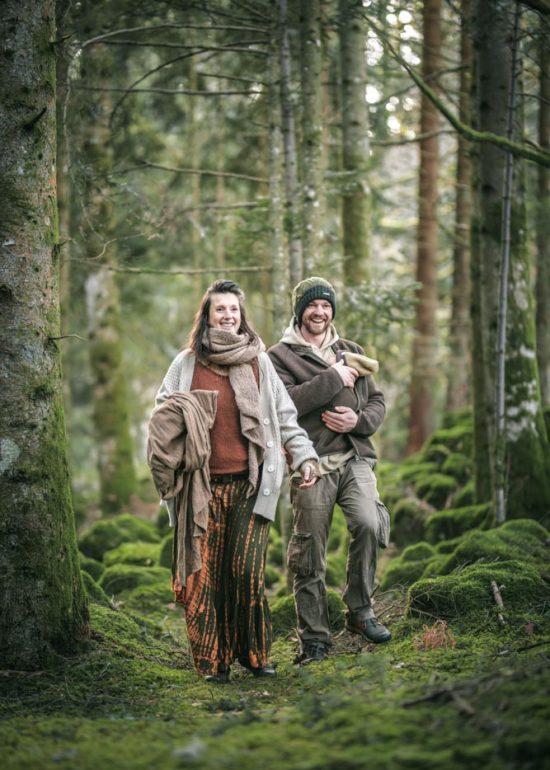 Photographie en plan large d'un couple souriant marchant en forêt