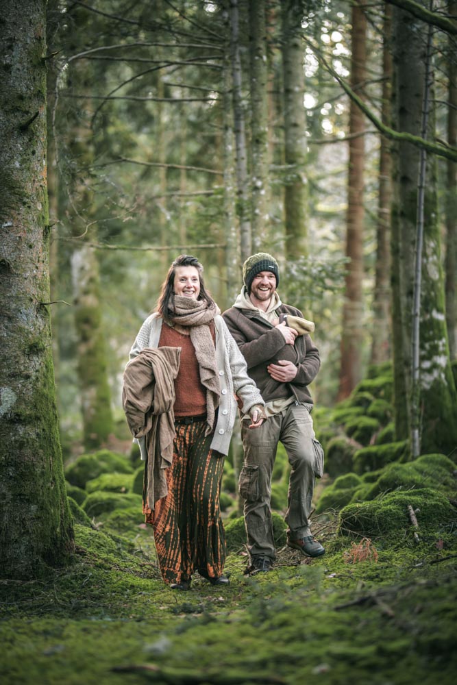 Photographie en plan large d'un couple souriant marchant en forêt
