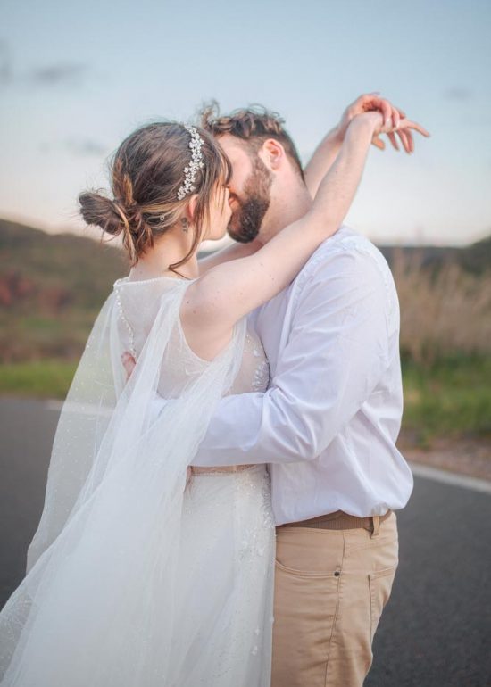 Plan serré d'un couple s'embrassant sur une route en montagne à l'heure bleue
