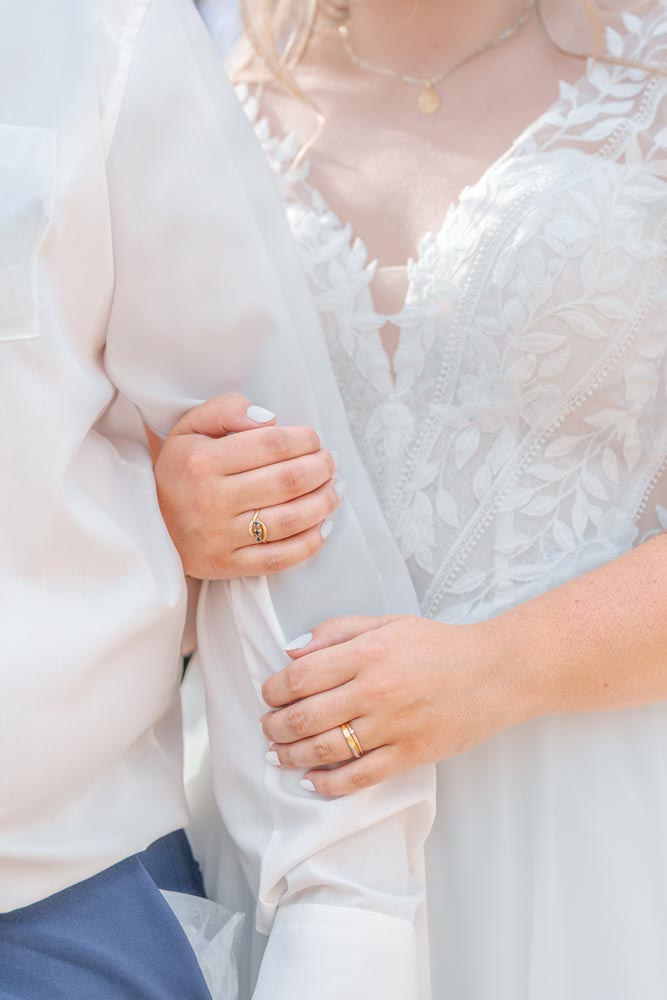 Plan serré sur les mains d'une marié tenant le bras de son époux