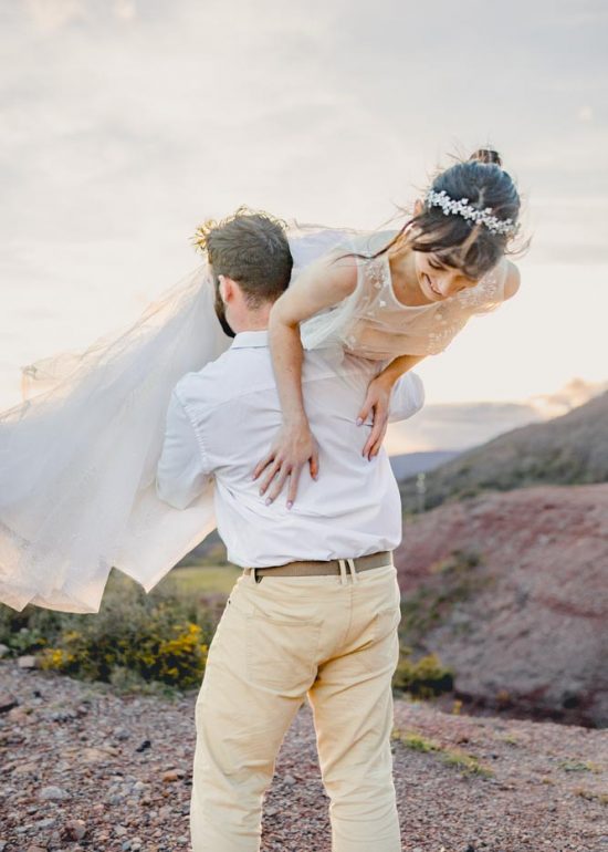 Plan moyen d'un marié portant son épouse hilare sur son épaule