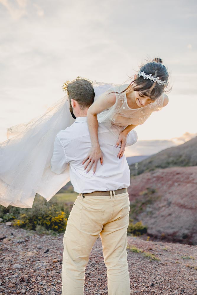 Plan moyen d'un marié portant son épouse hilare sur son épaule