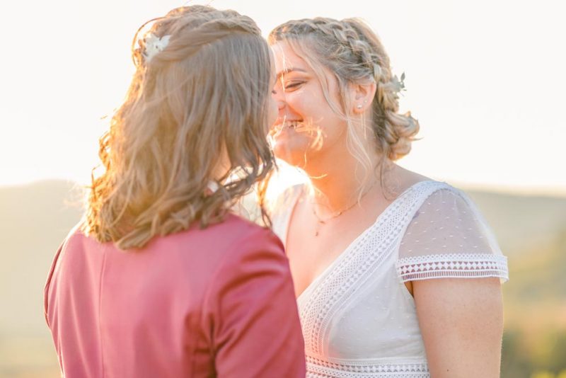 Plan serré d'un couple sur le point de s'embrasser et souriant baigné par la lumière du soleil couchant