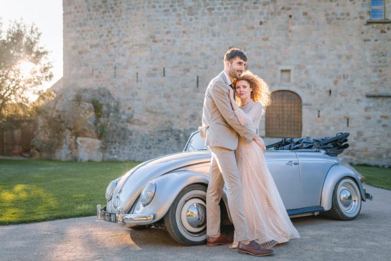 Couple enlacé dans une voiture de collection dans la cour d'un château au coucher de soleil