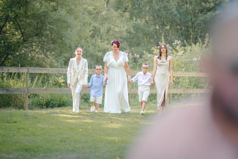 Une mariée et ses quatre enfants marchant en direction du marié, qu'on devine de dos, pour leur premier regard
