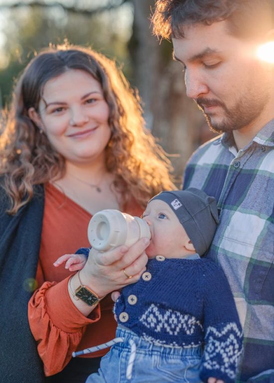 Couple nourrissant leur bébé dans le jardin familial au coucher de soleil