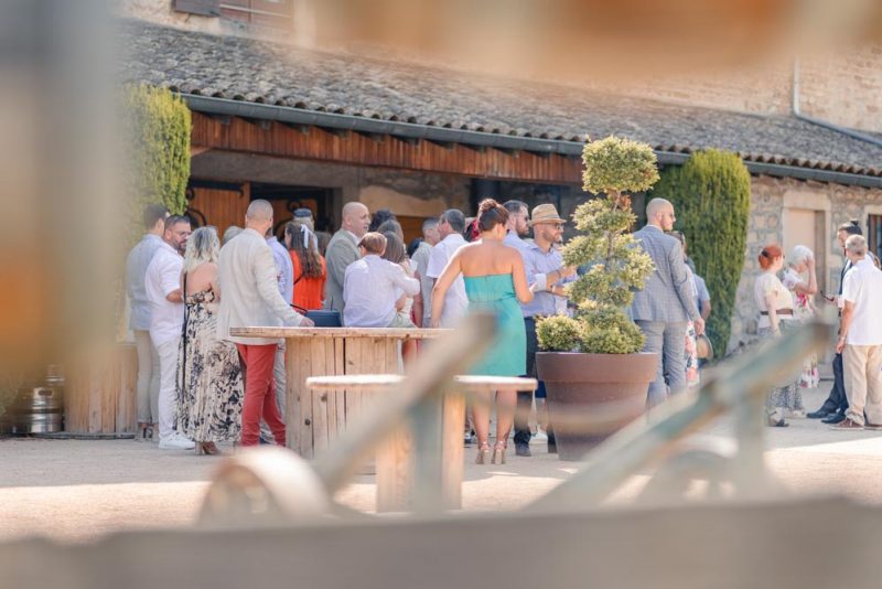 Invités durant le vin d'honneur pris en photo dans la cour du domaine, à travers la barrière