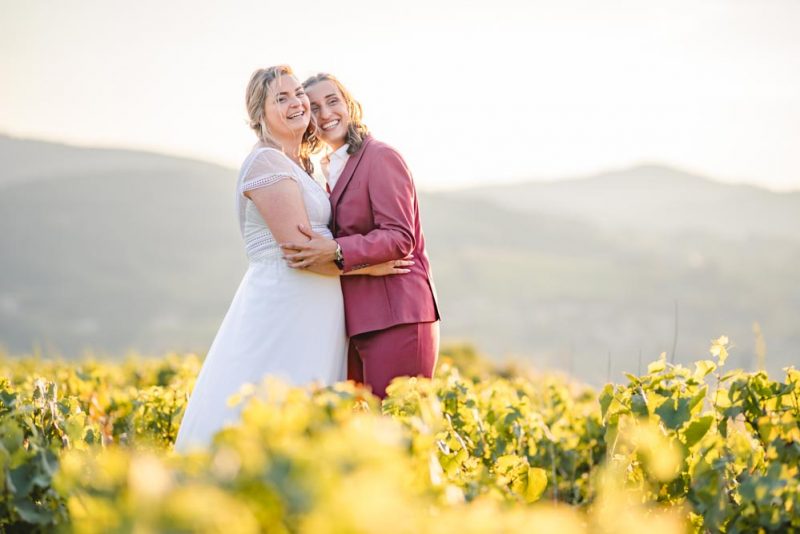 Plan large d'un couple enlacé et riant au milieu des vignes