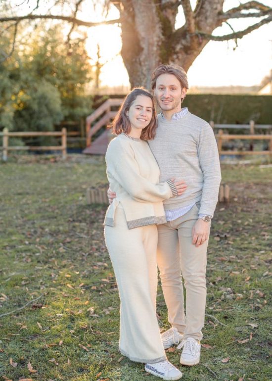 Couple en plan large serré l'un contre l'autre dans le jardin familial au coucher de soleil