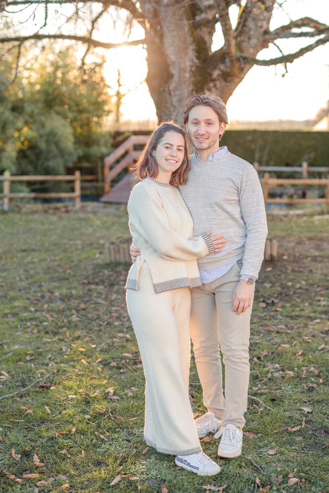 Couple en plan large serré l'un contre l'autre dans le jardin familial au coucher de soleil