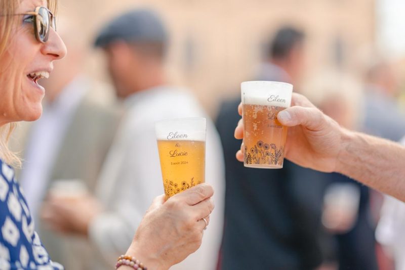 Plan serré sur deux verres à l'effigie des mariés durant le vin d'honneur