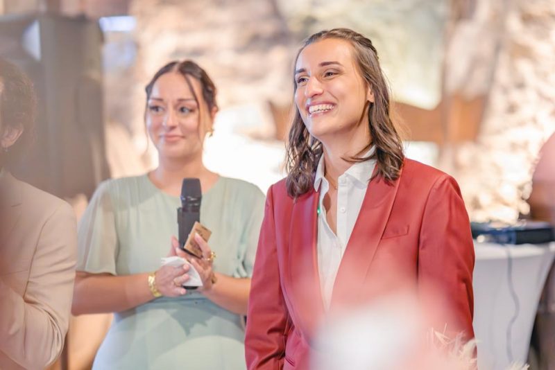 Photographie en plan serré de la mariée émue le sourire aux lèvres et les larmes aux yeux lors de l'entrée de sa future épouse