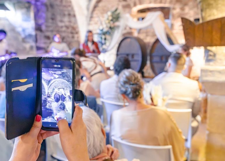 Gros plan sur un téléphone portable en train de prendre en photo les mariées durant la cérémonie
