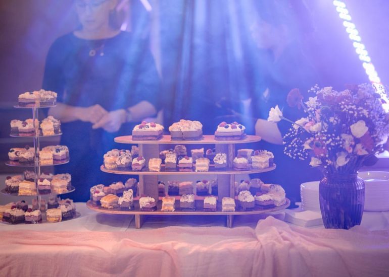 Dressage des parts de gâteau lors d'un mariage en intérieur baigné des lumières des spots