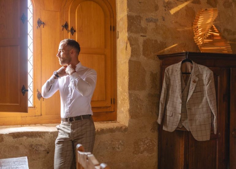 Futur marié s'habillant dans l'encadrure de la fenêtre pendant ses préparatifs