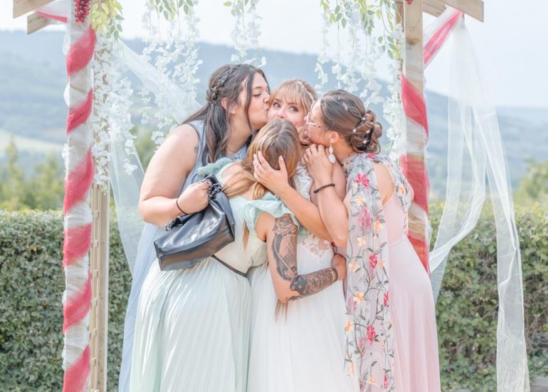 Photo de groupe des meilleures amies de la mariée qui l'embrassent toutes en même temps