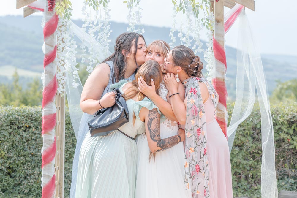 Photo de groupe des meilleures amies de la mariée qui l'embrassent toutes en même temps